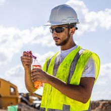 Construction worker pouring Sqwincher ZERO Qwik Stik into 16 oz bottle of water